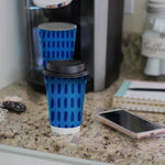 Chinet Comfort blue-patterned disposable cup with lid on a countertop next to a coffee maker and phone