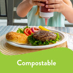 Close lifestyle shot of a burger on a Chinet white compostable plate with a person squeezing sauce above it.