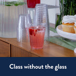 Stacked clear Chinet Crystal plastic cups on a table with one filled with a pink beverage and strawberries