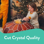 Child reaching toward a clear Chinet Crystal plate with snacks near a decorated Christmas tree, promotional banner below.