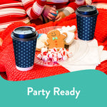 Clear Chinet Crystal plate with decorated cookies and peppermints on a red blanket, flanked by two takeaway coffee cups.