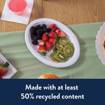 Top-down view of a white Chinet oval platter holding blackberries, strawberries and sliced kiwi on a green tablecloth