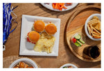 Overhead view of a wood table set with a Chinet white square plate holding sliders and potato chips among other appetizer dishes