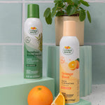 Styled product scene with Citrus Magic Bamboo Rainforest can alongside Orange Blast can and an orange on a tiled backdrop