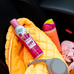 Citrus Magic Dragonfruit spray can placed on a quilted yellow bag inside a car next to headphones and a water bottle