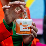 Person lifting the peel-back lid of a Citrus Magic Tropical Citrus air freshener can in a colorful lifestyle scene