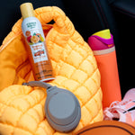 Citrus Magic Tropical Citrus spray can placed on a yellow quilted jacket among headphones, water bottle, and sneakers