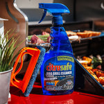Citrusafe spray bottle and orange scrubber displayed on a red grill side with food and grill in background.