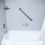 Clean white bathtub and tiled shower with grab bar and soap shelf, shot from bathroom interior