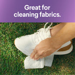 Hand using a wipe to clean a white sneaker on grass with a headline saying great for cleaning fabrics