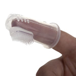 Clear silicone fingertip toothbrush fitted over an adult finger, showing short flexible bristles and textured rim