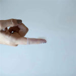 Close-up of an adult finger wearing a clear silicone baby finger toothbrush, displayed against a pale background