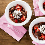 Styled overhead shot of dessert bowls with clear plastic spoons on napkins, showing spoon use in setting