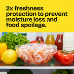 Refrigerator shelf with a glass bowl of shrimp covered in clear cling wrap and produce in background, headline about freshness