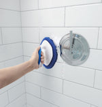 Hand using Clorox diamond scrubber on tiled shower wall, suds visible where scrubber contacts tile