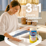 Lifestyle image of a person wiping a kitchen counter with a Clorox disinfecting wipes canister visible and '3 in 1' text overlay