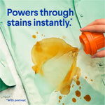 Hand pouring orange-capped product onto a green shirt stain with text 'Powers through stains instantly.'