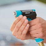 Close hand-held view of a Gilmour nozzle muzzle and grip, fingers wrapped around the black and teal body