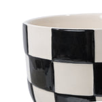 Close-up of the rim and upper section of a glossy black-and-white checkered ceramic planter.