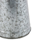 Close-up of the textured galvanized metal surface and lower rim of a tapered pitcher