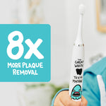 Close-up of a white Made By Dentists shark-themed electric toothbrush with turquoise graphic and '8x more plaque removal' badge.