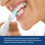 Close-up of person brushing teeth with an electric toothbrush producing foam along gum line