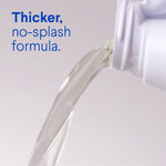 Close-up of liquid being poured from a white bottle with overlay text 'Thicker, no-splash formula.'
