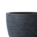 Close-up detail of a textured matte black ceramic plant pot showing horizontal rough grooves