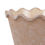 Close-up of the scalloped wavy rim and textured brown surface of a ceramic planter.