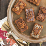 Close-up of baked mini loaves on a round metal tray showing detailed harvest shapes like a squirrel and leaf