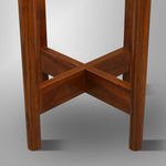 Close-up of crossed wooden support pieces at base of antique mahogany plant stand showing wood grain and joinery