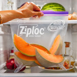 Close-up of a hand holding a Ziploc heavy duty bag filled with cantaloupe slices inside a refrigerator, purple zipper visible.