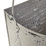 Close-up detail of a distressed painted metal bucket showing handle attachment and textured finish