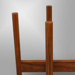 Close-up vertical view of two round mahogany legs and a horizontal support of a wooden plant stand on gray background