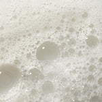 Close-up overhead shot of white soap bubbles and foam filling the frame.