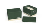 Three Coleman green cooler-style tins, one with lid removed showing two-wick white candle inside