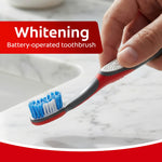 Hand holding a Colgate 360 battery-operated toothbrush angled over a sink with 'Whitening' label graphic