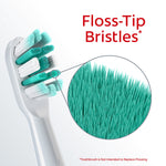 Colgate brush head close-up with magnified circular inset showing dense teal floss-tip bristles, labeled Floss-Tip Bristles