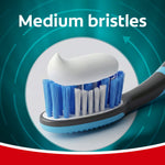 Colgate toothbrush head loaded with toothpaste showing medium bristles on a circular teal infographic background.