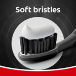 Toothbrush head with soft charcoal bristles topped with a dollop of toothpaste and 'Soft bristles' label.