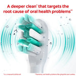 Close-up of Colgate Total toothbrush head with teal and white bristles, water droplets and waves emphasizing deeper clean