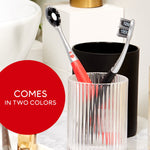 Two Colgate Optic White Pro Series toothbrushes placed in bathroom holders, one red and one black, with a red label reading comes in two colors