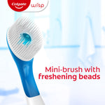 Close-up of a blue-and-white Colgate Wisp mini-brush head showing white bristles and a central freshening bead against a blurred bathroom background.