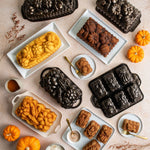 Assortment of Nordic Ware harvest loaf pans and molded loaves arranged with small pumpkins and serving plates