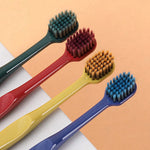 Close-up of four colorful manual toothbrushes laid diagonally showing dense, rounded bristle heads.