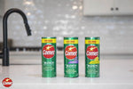 Three Comet powder cans standing on a kitchen counter with a tiled backsplash, center can labeled lavender.