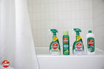 Bathroom scene with a tiled tub edge displaying multiple Comet-branded cleaning bottles and sprays.