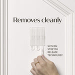 Hand pulling a Command adhesive strip from a wall with headline ‘Removes cleanly’ and note about 3M stretch release technology