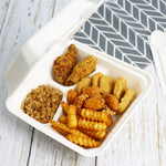 Open white compostable 3-compartment container holding fried chicken, fries and rice on a wood surface