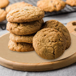 Stack of cookies arranged on a round unbleached parchment sheet set on a wooden serving board.